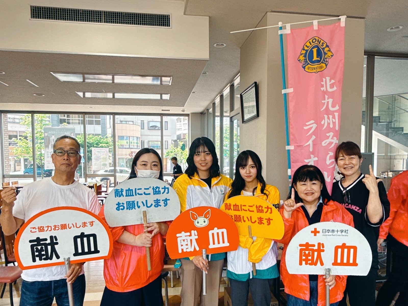 献血への協力を呼びかけるプラカードを持ったメンバーと学生のみなさん